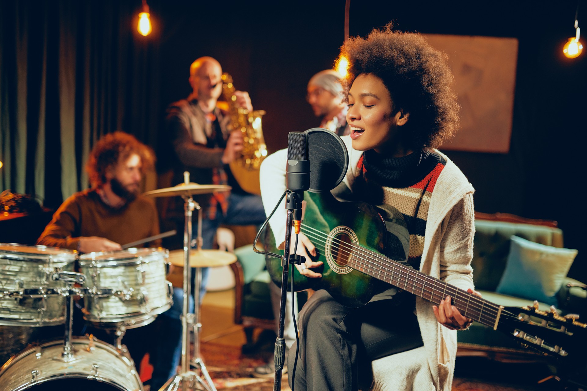 Mixed race woman singing and playing guitar.